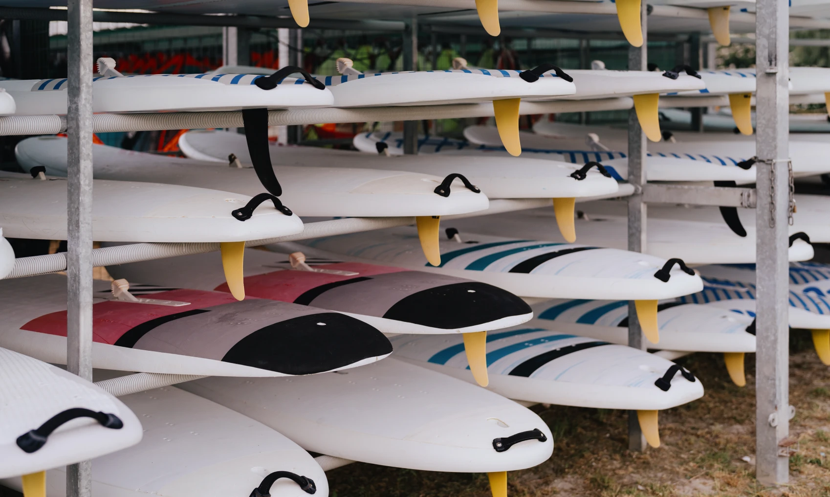 Stacked surfboards on metal storage racks.